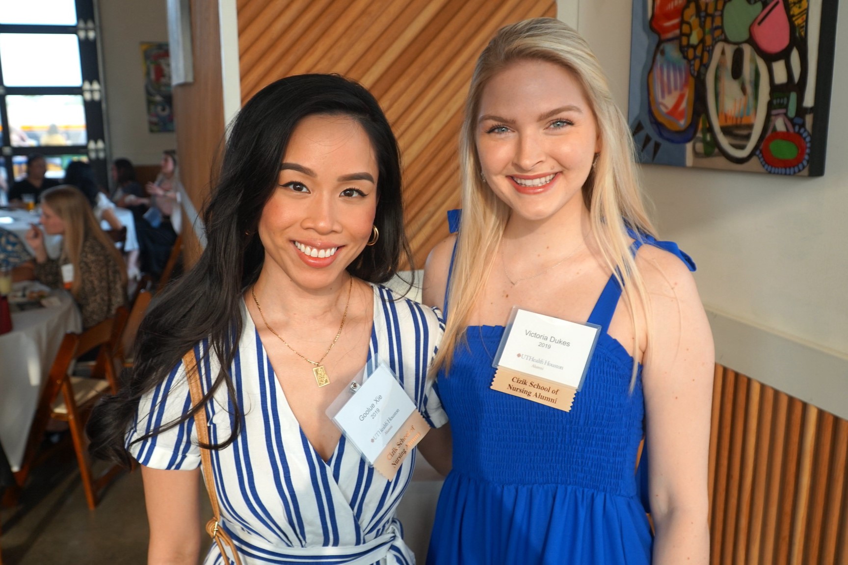 Two women posing with name tags on, smiling at a camera.