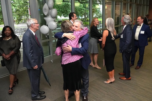 Alumni gathering and two people hugging at an alumni event