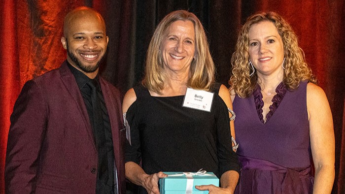 Three people standing together during an awards ceremony