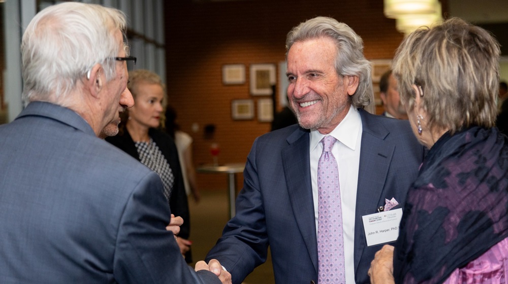 Distinguished Alumnus award winner shaking hands with another person at an event