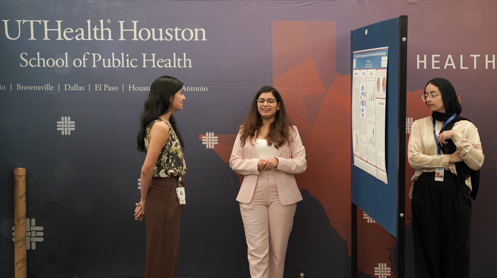 Three female School of Public Health students looking at a presentation